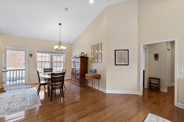 dining area featuring dark wood-type flooring, high vaulted ceiling, and a notable chandelier