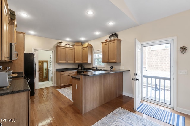 kitchen with sink, stainless steel appliances, kitchen peninsula, and light wood-type flooring