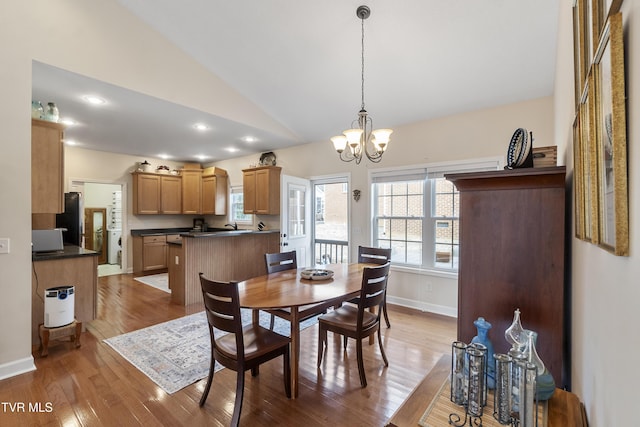 dining area with hardwood / wood-style flooring, lofted ceiling, and a chandelier