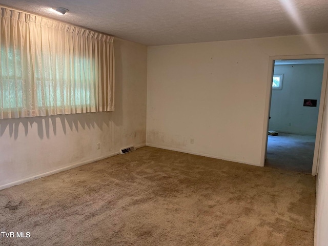 carpeted empty room featuring a textured ceiling