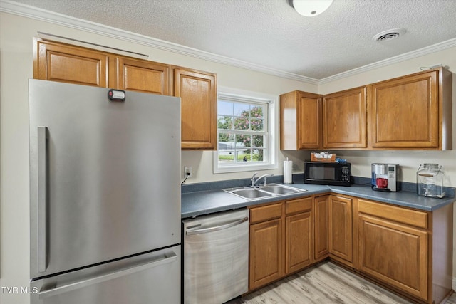 kitchen with sink, ornamental molding, stainless steel appliances, and a textured ceiling