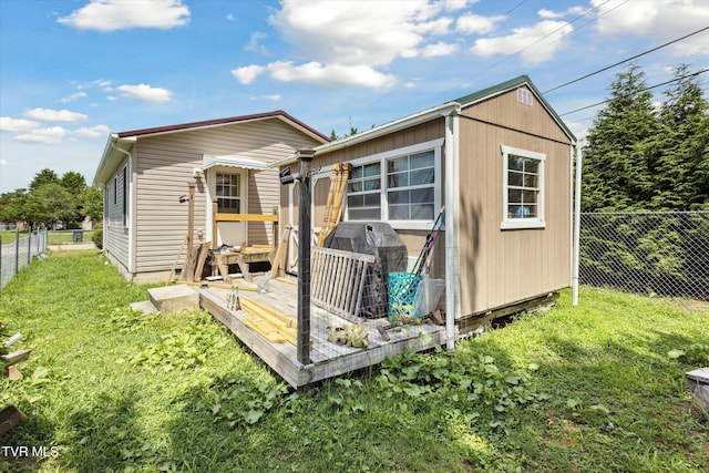 back of house featuring a wooden deck, an outdoor structure, and a yard