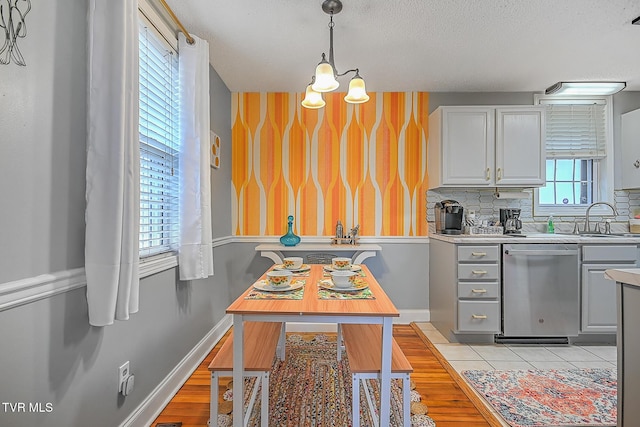 kitchen with sink, dishwasher, gray cabinetry, hanging light fixtures, and backsplash