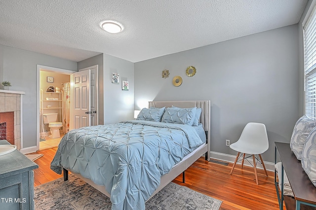 bedroom with ensuite bath, a textured ceiling, and light wood-type flooring