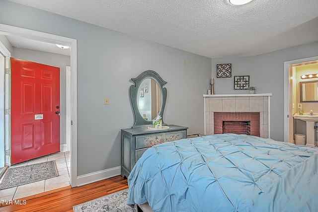 bedroom featuring ensuite bath, a textured ceiling, and light wood-type flooring