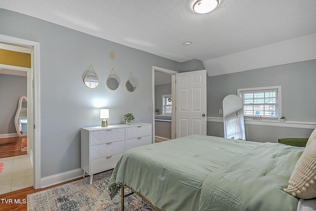 bedroom featuring lofted ceiling, hardwood / wood-style floors, and a textured ceiling