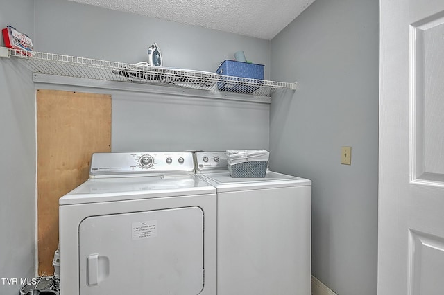 clothes washing area with washer and dryer and a textured ceiling