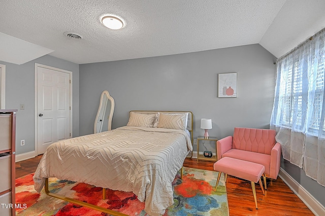 bedroom featuring hardwood / wood-style flooring, lofted ceiling, and a textured ceiling