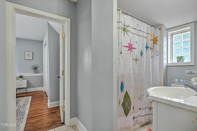 bathroom with a shower with curtain, vanity, tile patterned flooring, and a textured ceiling