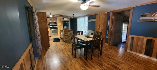 dining area with lofted ceiling, hardwood / wood-style floors, ceiling fan, and wood walls