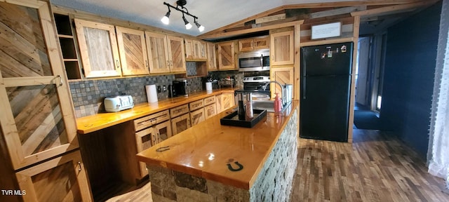 kitchen with appliances with stainless steel finishes, hardwood / wood-style floors, lofted ceiling, and backsplash