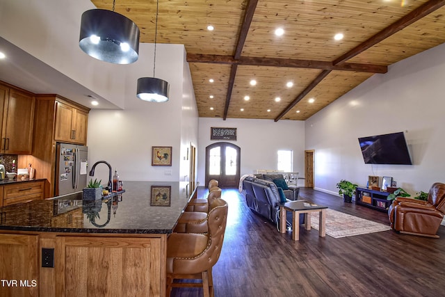 kitchen with pendant lighting, stainless steel fridge, dark hardwood / wood-style flooring, and dark stone countertops