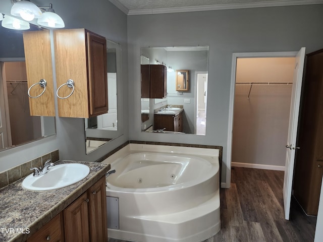 bathroom with wood-type flooring, a bathtub, vanity, crown molding, and a textured ceiling