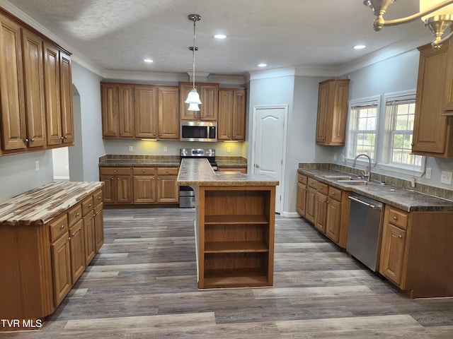 kitchen with sink, appliances with stainless steel finishes, a center island, dark hardwood / wood-style flooring, and decorative light fixtures