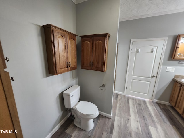 bathroom with hardwood / wood-style flooring, vanity, ornamental molding, a textured ceiling, and toilet