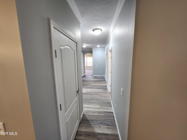 hall with light hardwood / wood-style flooring, ornamental molding, and a textured ceiling