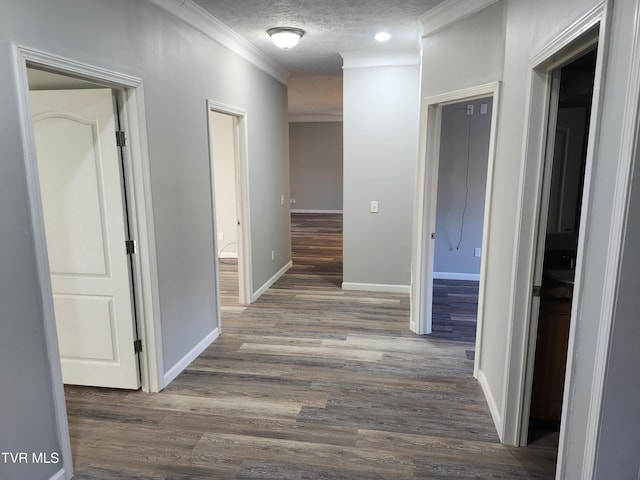 corridor featuring hardwood / wood-style flooring, ornamental molding, and a textured ceiling