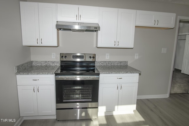 kitchen with white cabinetry, light stone counters, stainless steel electric range, and light wood-type flooring