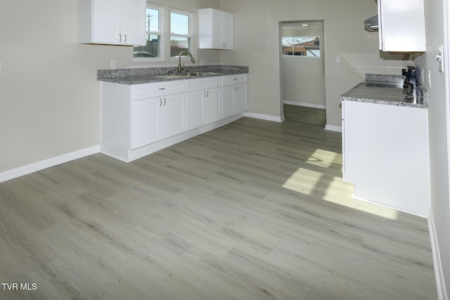 kitchen with white cabinetry, stone countertops, sink, and light hardwood / wood-style floors