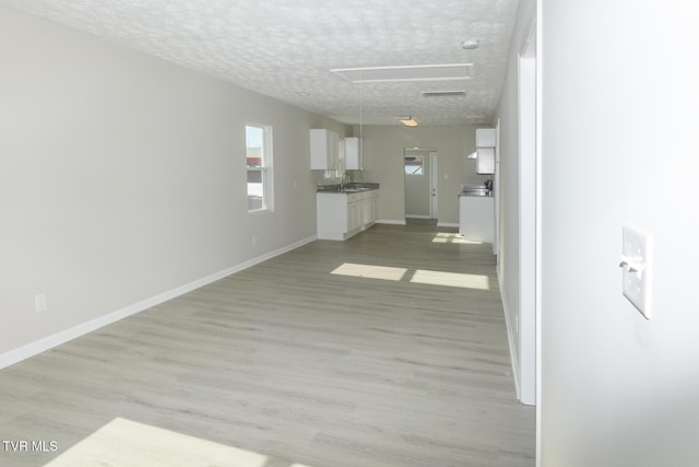 hallway featuring sink, light hardwood / wood-style flooring, and a textured ceiling