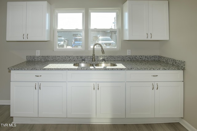 kitchen with light stone countertops, sink, and white cabinets