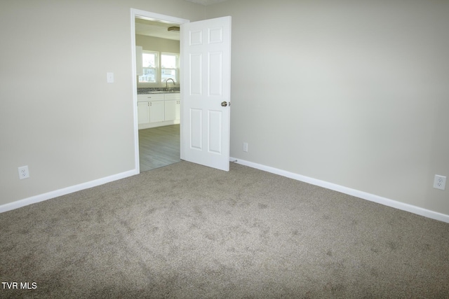 unfurnished room with sink and dark colored carpet