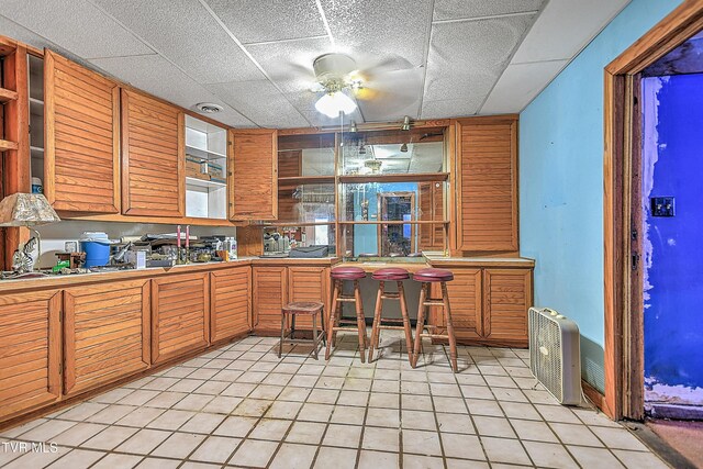 169 Church Cir, Bristol, TN 37620 - kitchen featuring a ceiling fan, light tile patterned floors, a drop ceiling, and brown cabinets