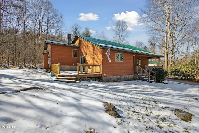 snow covered back of property featuring a deck