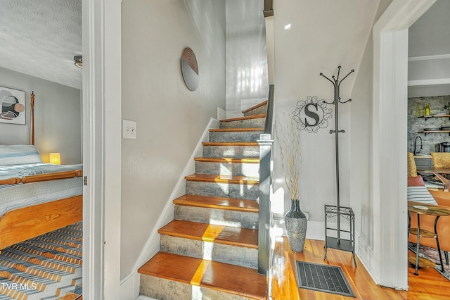 stairway featuring sink, hardwood / wood-style floors, and a textured ceiling