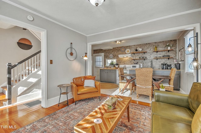 living room with ornamental molding, plenty of natural light, a textured ceiling, and light hardwood / wood-style flooring