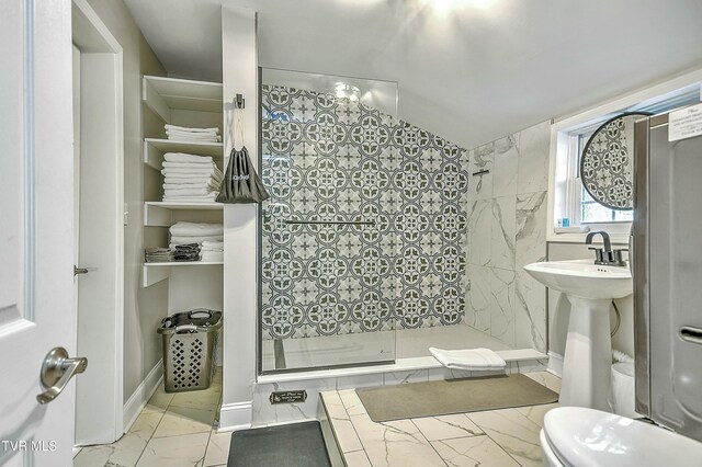 bathroom featuring a tile shower, vaulted ceiling, and toilet