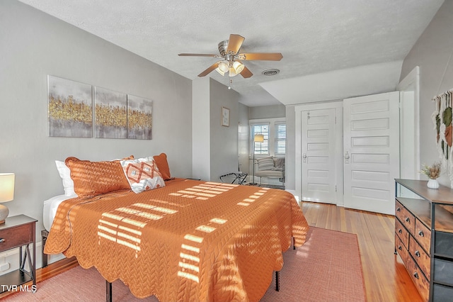 bedroom with ceiling fan, a closet, a textured ceiling, and light wood-type flooring