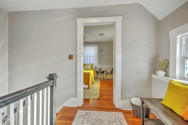 hallway with hardwood / wood-style flooring and vaulted ceiling