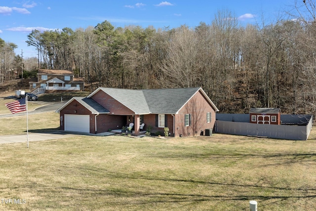 view of front of home with a garage, a front yard, and a storage shed