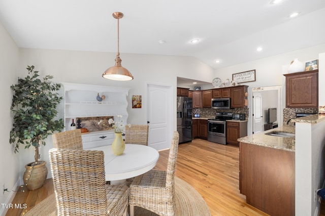 dining room with lofted ceiling, sink, and light hardwood / wood-style floors