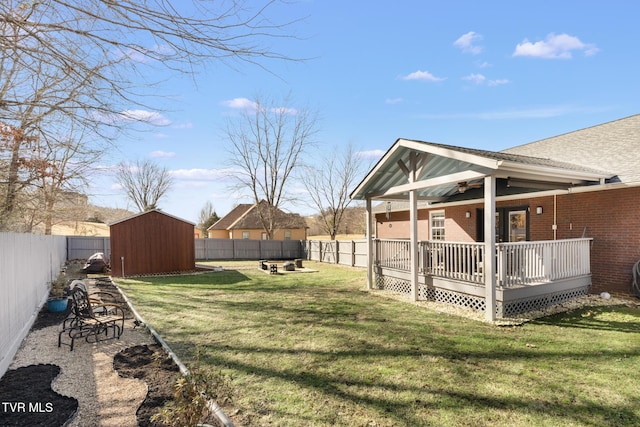 view of yard with an outdoor fire pit, a deck, and a storage shed