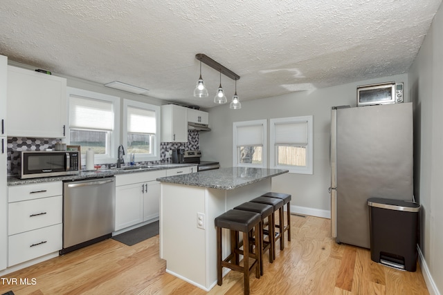 kitchen featuring white cabinetry, appliances with stainless steel finishes, a center island, and sink