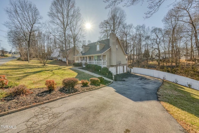 view of side of home with a garage, covered porch, and a lawn