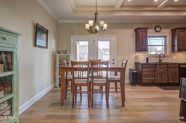 dining space featuring sink, a notable chandelier, ornamental molding, light hardwood / wood-style floors, and beamed ceiling