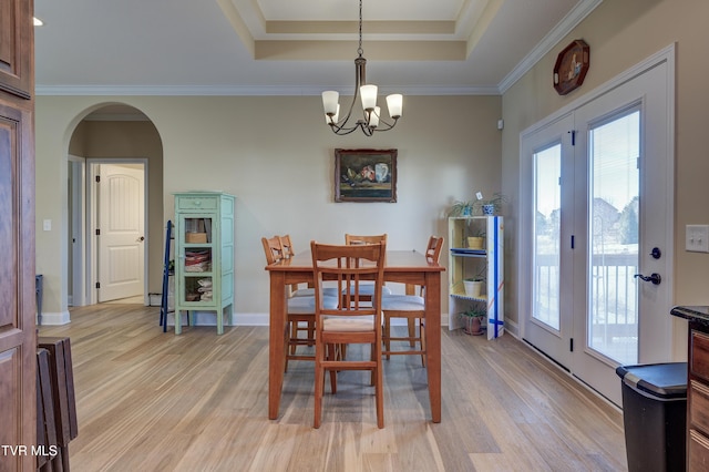 dining area with a chandelier, crown molding, a raised ceiling, and light wood-type flooring