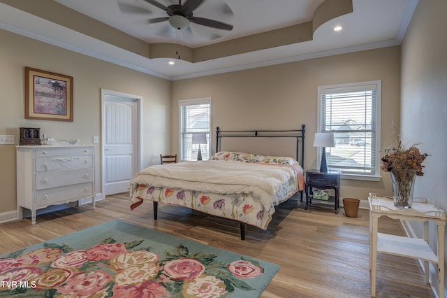 bedroom featuring crown molding, light hardwood / wood-style flooring, and a tray ceiling