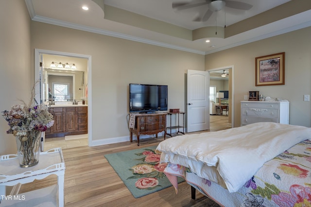 bedroom featuring a tray ceiling, ornamental molding, light hardwood / wood-style floors, and ensuite bath