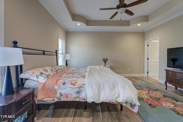 bedroom featuring a raised ceiling, crown molding, hardwood / wood-style flooring, and ceiling fan