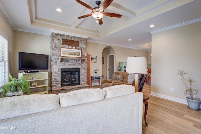 living room with a fireplace, beamed ceiling, ceiling fan, crown molding, and light hardwood / wood-style flooring