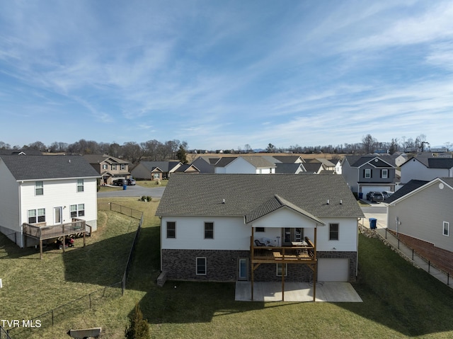 rear view of property with a garage, a wooden deck, a yard, and a patio area