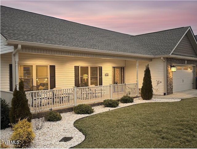 view of front of home featuring a porch, a garage, and a lawn