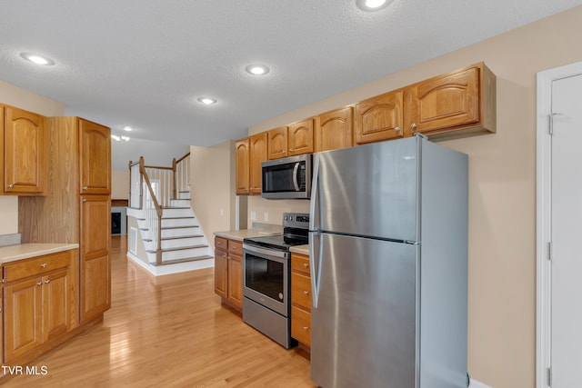 kitchen featuring appliances with stainless steel finishes, a textured ceiling, and light hardwood / wood-style flooring