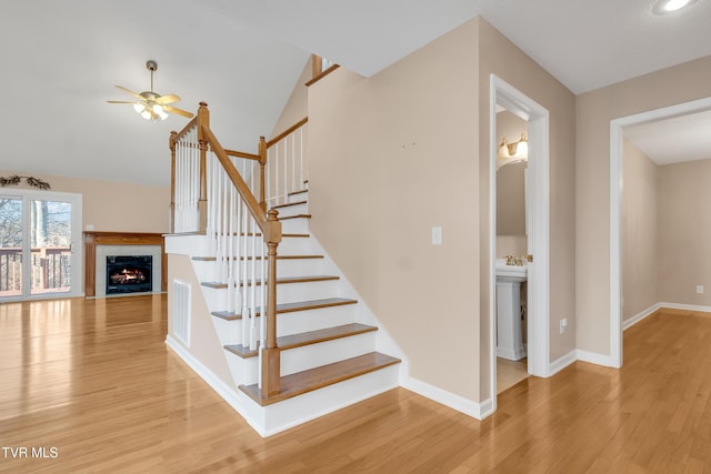 staircase with hardwood / wood-style flooring, vaulted ceiling, and ceiling fan