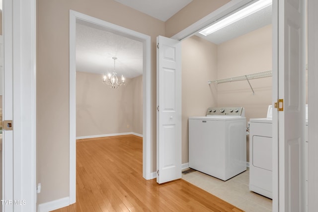 washroom with wood-type flooring, a chandelier, and washing machine and dryer