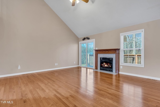 unfurnished living room featuring a fireplace, light hardwood / wood-style flooring, high vaulted ceiling, and ceiling fan